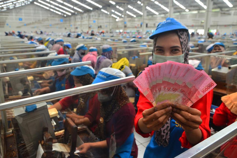 Pekerja menunjukkan uang Tunjangan Hari Raya (THR) yang diterimanya di pabrik rokok PT Djarum, Kudus, Jawa Tengah, Selasa (19/4/2022). Sebanyak 52.025 pekerja harian dan borongan yang tersebar di tujuh kota di perusahaan itu telah menerima uang THR guna m