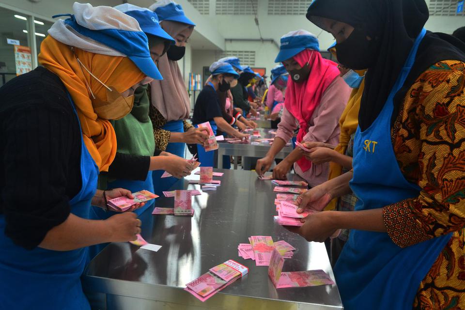 Pekerja menghitung uang Tunjangan Hari Raya (THR) yang diterimanya di pabrik rokok PT Djarum, Kudus, Jawa Tengah, Selasa (19/4/2022). Sebanyak 52.025 pekerja harian dan borongan yang tersebar di tujuh kota di perusahaan itu telah menerima uang THR guna me