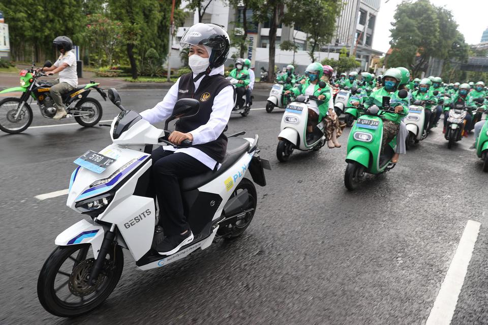 Gubernur Jawa Timur Khofifah Indar Parawansa (kiri) mengendarai motor listrik GESITS saat mengikuti konvoi bersama 100 pengemudi ojek daring perempuan di Surabaya, Jawa Timur, Kamis (21/4/2022). 