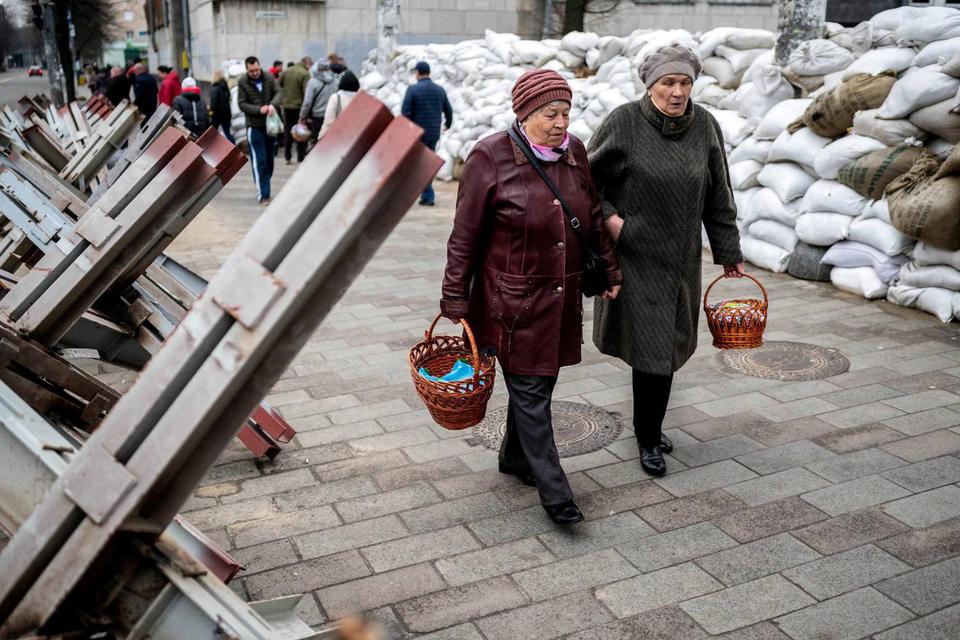 Viacheslav Ratynskyi Jemaat berjalan diantara karung pasir dan landak barikade anti-tank untuk menghadiri pemberkatan keranjang makanan Paskah tradisional pada Sabtu Suci, ditengah serbuan Rusia di Ukraina, di Zhytomyr, Ukraina, Sabtu (23/4/202