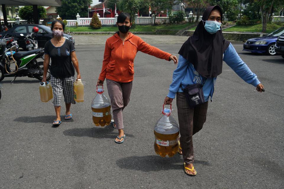 Warga membawa minyak goreng curah yang dibeli saat Operasi Pasar Minyak Goreng Curah di Gedung Serbaguna Pemkab Sleman, D.I Yogyakarta, Kamis (28/4/2022).