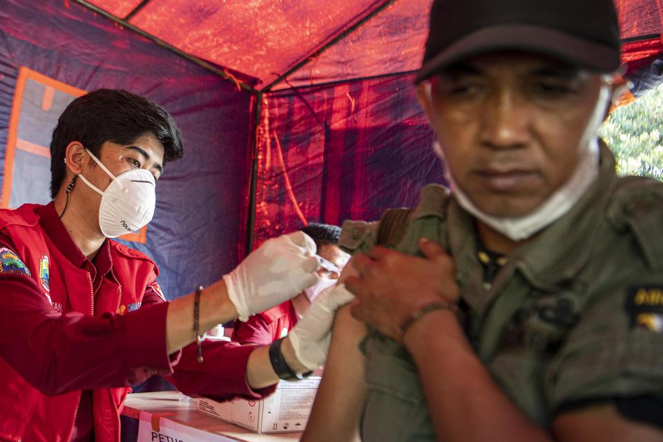 Petugas Puskesmas menyuntikkan vaksin Covid-19 dosis ketiga (booster) kepada pemudik di terminal keberangkatan Pelabuhan Bakauheni, Lampung Selatan, Lampung, Sabtu (30/4/2022).