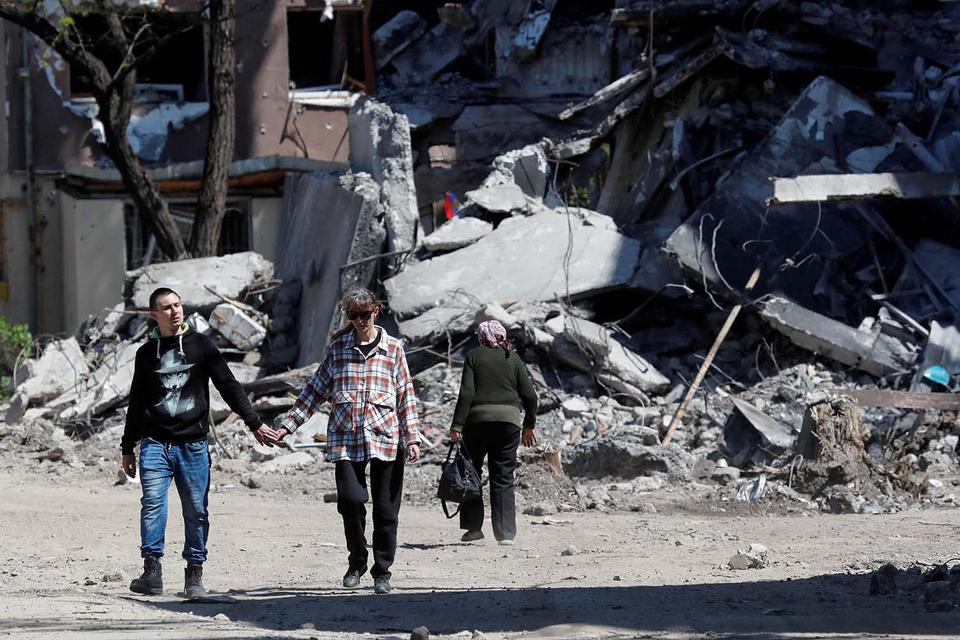 Alexander Ermochenko. Warga lokal berjalan melewati bangunan yang hancur saat konflik Ukraina-Rusia di selatan kota pelabuhan Mariupol, Ukraina, Kamis (12/5/2022).