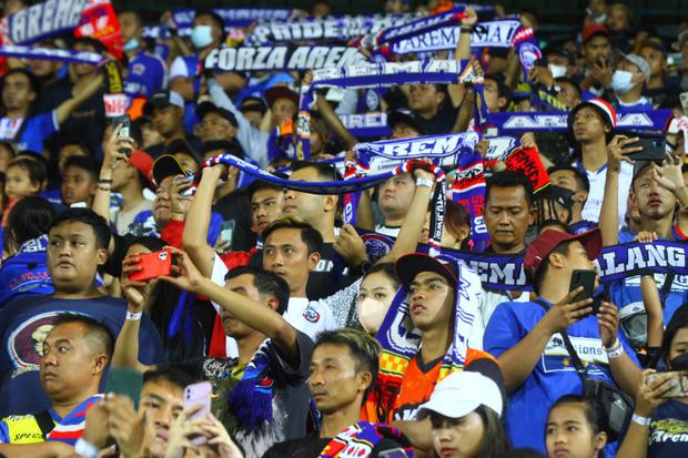 Suporter kesebelasan Arema FC atau Aremania mengangkat syal untuk memberi semangat kepada tim kesayangannya di Stadion Kanjuruhan, Malang, Jawa Timur, Minggu (22/5/2022). 