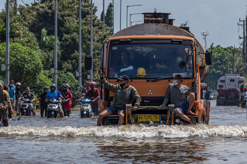 Ilustrasi, sejumlah pekerja pelabuhan menumpang truk untuk dapat menerobos banjir limpasan air laut ke daratan atau banjir rob yang merendam kawasan Pelabuhan Tanjung Emas, Semarang, Jawa Tengah, Selasa (24/5/2022).