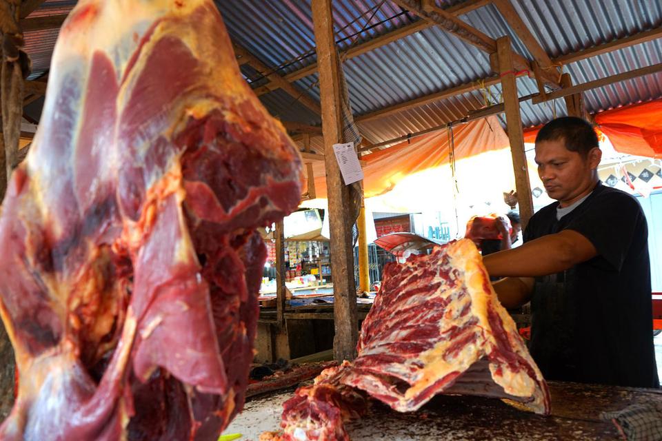 Pedagang memotong daging sapi pesanan pembeli di Pasar Sentral, Kota Gorontalo, Gorontalo, Jumat (27/5/2022). Sejumlah pedagang mengaku Penyakit Mulut dan Kuku (PMK) yang menyerang hewan ternak di beberapa daerah di Indonesia tidak berpengaruh pada penjua
