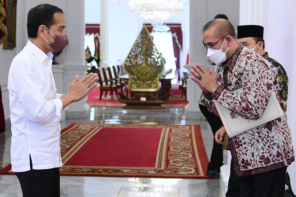 Presiden Joko Widodo (kiri) menerima kedatangan Ketua KPU Hasyim Asy'ari (kanan) untuk melakukan pertemuan di Istana Merdeka, Jakarta, Senin (30/5/2022). 