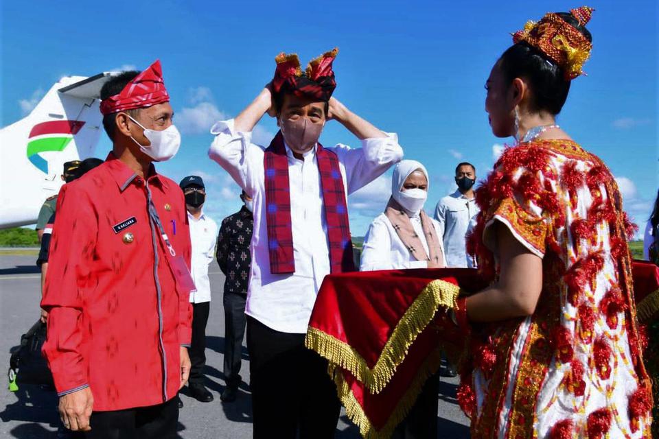 Presiden Joko Widodo (tengah) mengenakan topi adat Wakatobi didampingi Bupati Wakatobi Haliana (kiri) saat tiba di Bandar Udara Matohara di Wakatobi, Sulawesi Tenggara, Kamis (9/6/2022). 