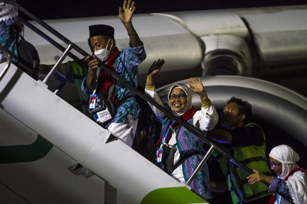 Jamaah calon haji melambaikan tangan saat menaiki tangga menuju pesawat Airbus 330-300 di Bandara Internasional Syamsudin Noor, Banjarbaru, Kalimantan Selatan, Minggu (12/6/2022) malam. Sebanyak 360 jamaah calon haji kelompok terbang (kloter) pertama emba