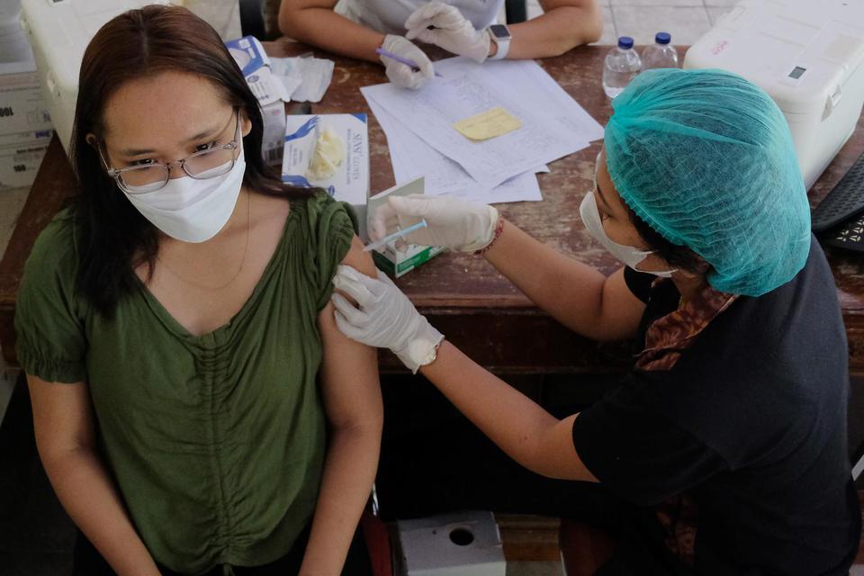 Petugas kesehatan menyuntikkan vaksin dosis ketiga kepada warga di Denpasar, Bali, Selasa (14/6/2022). 
