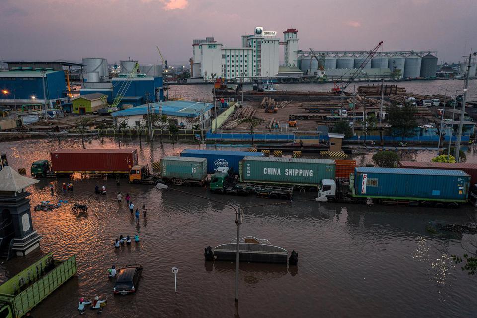Foto udara sejumlah truk pengangkut kontainer mengantre untuk menembus banjir limpasan air laut ke daratan atau rob yang merendam kawasan Pelabuhan Tanjung Emas Semarang, Jawa Tengah, Senin (20/6/2022). Banjir rob dengan ketinggian bervariasi hingga menca