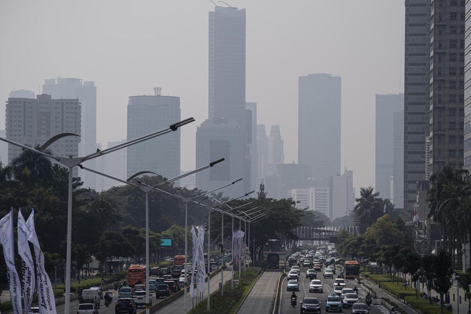 Kendaraan melintas dengan latar belakang gedung bertingkat yang terlihat berkabut di Jalan Jenderal Sudirman, Jakarta, Rabu (22/6/2022). Menurut data dari laman lembaga kualitas udara IQAir, pada Rabu 22 Juni 2022 hingga pada pukul 11.00 WIB indeks pencem