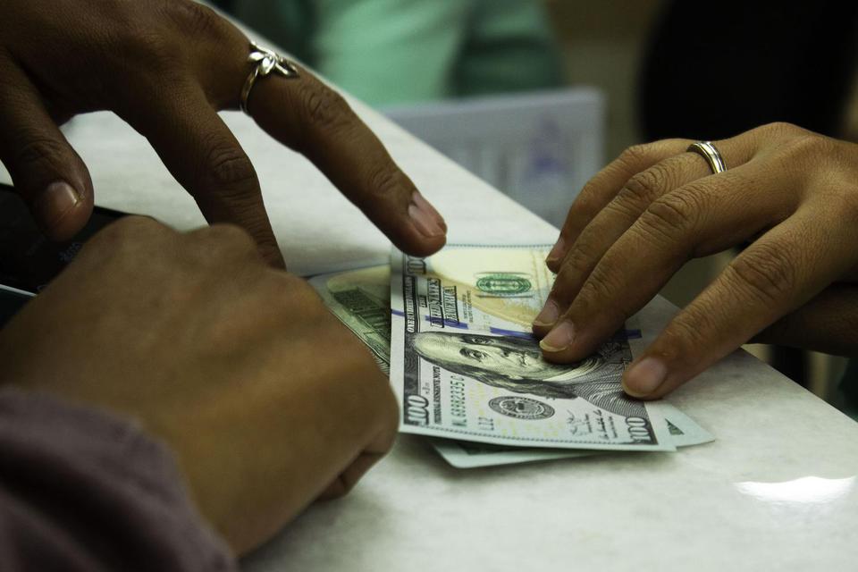 Teller melayani jual beli mata uang Dolar AS di sebuah tempat penukaran uang, Jakarta. 