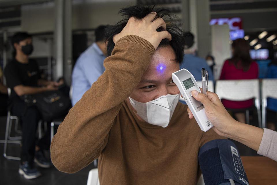 Petugas mengukur suhu tubuh calon penerima vaksin COVID-19 di Stasiun Manggarai, Jakarta Selatan, Rabu (13/7/2022). 