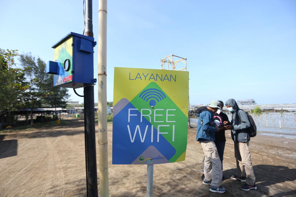 Warga menggunakan layanan wifi gratis di objek wisata Karangsong, Indramayu, Jawa Barat, Jumat (29/7/2022). 