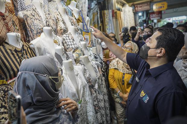 Menteri BUMN Erick Thohir (kanan) melihat produk baju saat menghadiri Program Livin' Pasar Mandiri di Pasar Beringharjo, Yogyakarta, Kamis (11/8/2022). Dalam kegiatan tersebut Bank Mandiri berupaya membudayakan transaksi digital para pedagang di sejumlah