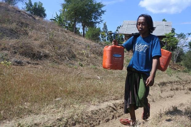 Seorang warga memikul jeriken berisi air bersih usai mengambil di sumur yang mulai berkurang debit airnya di Desa Jatisari, Arjasa, Situbondo, Jawa Timur, Jumat (19/8/2022). Warga Desa Jatisari setiap tahunnya selalu menemui kesulitan mengakses air bersih