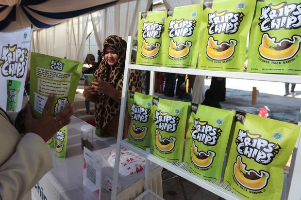 Pengunjung memindai kode batang pembayaran non tunai untuk produk kerajinan rumah tangga di pasar rakyat dan bazaar UMKM BUMN, Banda Aceh, Aceh, Jumat (19/8/2022). Sebanyak 50 UMKM Binaan BUMN yang terdiri dari produk makanan, minuman, pakaian dan berbaga