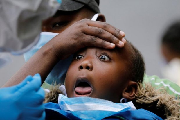 A young girl reacts as a Kenyan ministry of health medical worker takes a swab during mass tasting in an effort to fight against the spread of the coronavirus disease (COVID-19) in the Kawangware neighborhood of Nairobi, Kenya, May 2, 2020. REUTERS/Baz Ra