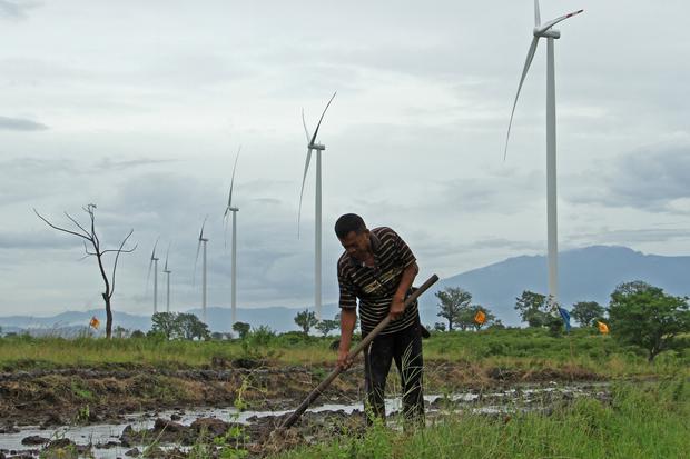Petani menggarap sawahnya di sekitar lokasi Pembangkit Listrik Tenaga Bayu (PLTB) Tolo, Kabupaten Jeneponto, Sulawesi Selatan, Minggu (27/11/2022). Kementerian Energi Sumber Daya Mineral (ESDM) menargetkan kapasitas pembangkit energi bersih pada tahun 206