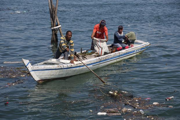 Sejumlah petugas kebersihan berusaha mengangkat sampah di laut yang terbawa arus di Pulau Belakang Padang, Batam, Kepulauan Riau, Senin (28/11/2022). 