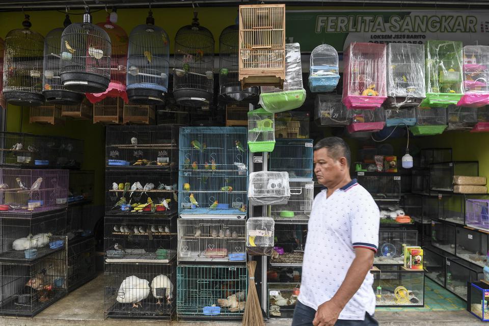 Warga melintas di depan kios pedagang hewan di Pasar Barito, Jakarta,