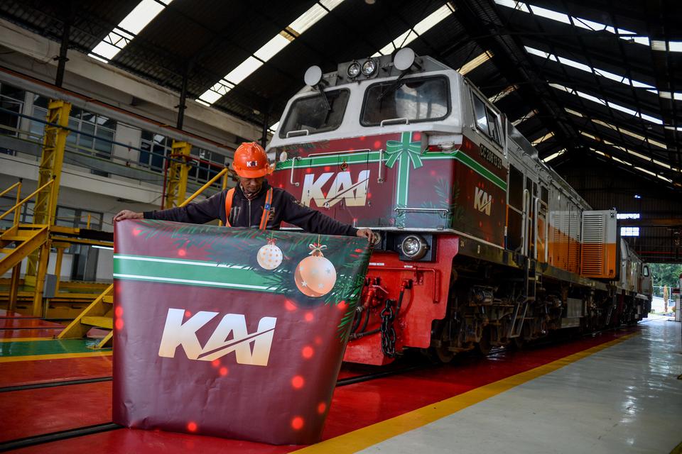 Pekerja menunjukan stiker dengan ornamen natal di depan sebuah lokomotif di depo lokomotif Stasiun Bandung, Jawa Barat, Jumat (23/12/2022). PT KAI Daop 2 Bandung mempersiapkan 26 lokomotif dan 147 kereta penumpang guna mendukung masa liburan Natal dan Tah