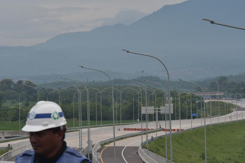 Pekerja melintas di samping pembangunan Tol Cisumdawu (Cileunyi-Sumedang-Dawuan) seksi 6 di Kabupaten Majalengka, Jawa Barat, Rabu (28/12/2022). Menurut Kementerian Koordinator Bidang Perekonomian melalui KPPIP (Komite Percepatan Penyediaan Infrastruktur 