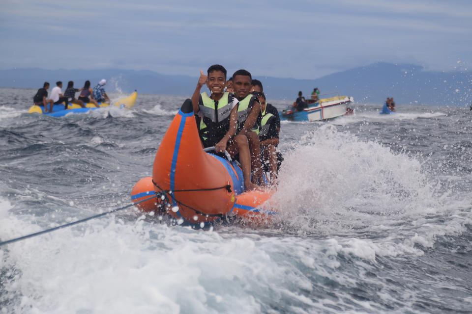 Sejumlah pengunjung menaiki wahana " Banana Boat" saat libur Tahun Baru 2023 di objek wisata Pantai Jikomalamo, Kota Ternate, Maluku Utara, Minggu (1/1/2023).