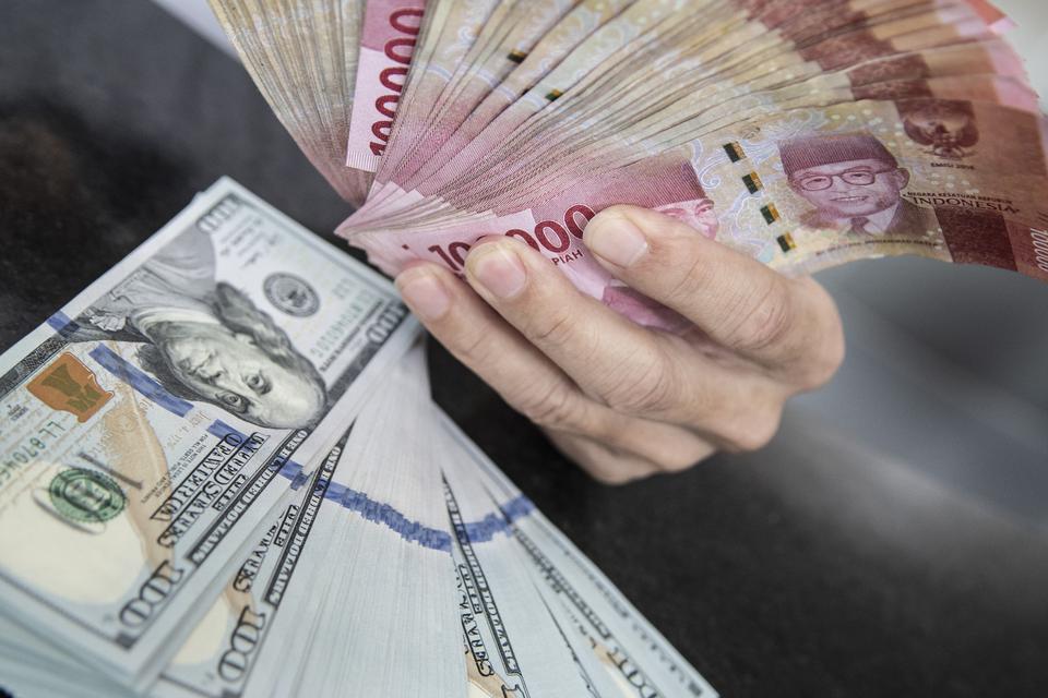 Petugas menunjukan uang pecahan rupiah dan dolar AS di gerai penukaran mata uang asing VIP (Valuta Inti Prima) Money Changer, Jakarta, Selasa (3/1/2023). Rupiah ditutup melemah 28 poin atau 0,18 persen ke posisi Rp15.601 per dolar AS dibandingkan posisi p