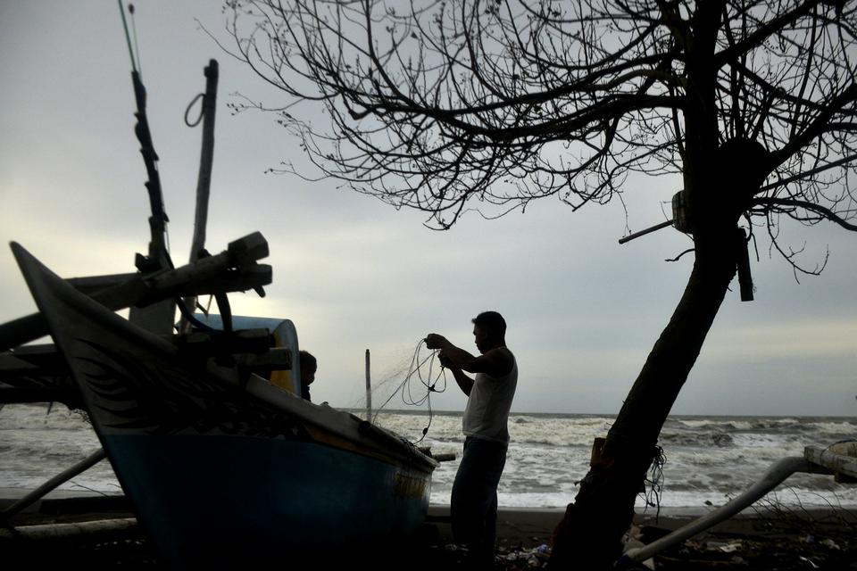 Nelayan memperbaiki jaring saat tidak melaut di Kecamatan Galesong Utara, Kabupaten Takalar, Sulawesi Selatan, Selasa (3/1/2023). Sejak dua pekan terakhir nelayan di daerah tersebut tidak melaut akibat angin kencang dan gelombang tinggi, sementara para ne