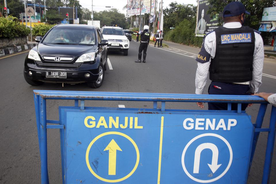 Petugas Sat Lantas Polres Bogor dan petugas Dishub Kabupaten Bogor mengarahkan kendaraan wisatawan saat penyekatan kendaraan nomor polisi ganjil genap di jalur wisata Puncak, Gadog, Kabupaten Bogor, Jawa Barat, Minggu (22/1/2023).