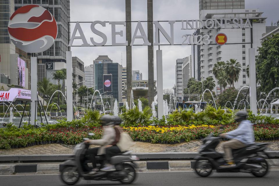 Pengendara motor melintas di depan logo KTT ASEAN Summit 2023 di Bundaran HI, Jakarta, Jumat (27/1/2023). 