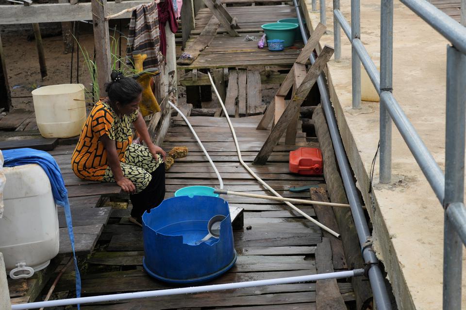 Seorang ibu menampung air bersih pegunungan di depan rumahnya di Desa Leppe, Konawe, Sulawesi Tenggara, Selasa (7/2/2023). Pemerintah melalui Kementerian PUPR telah melaksanakan Program Penyediaan Air Minum dan Sanitasi Berbasis Masyarakat (PAMSIMAS) seja