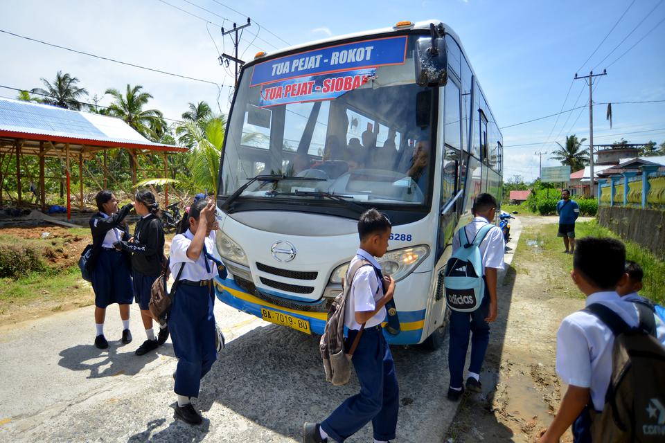 Sejumlah pelajar turun dari Bus Damri di Kilometer 10 Jalan Raya Tua Pejat, Kabupaten Kepulauan Mentawai, Sumatera Barat, Selasa (7/2/2023). Bus Damri sebagai angkutan perintis untuk daerah 3T di Mentawai yang selama ini melayani transportasi darat Tua Pe