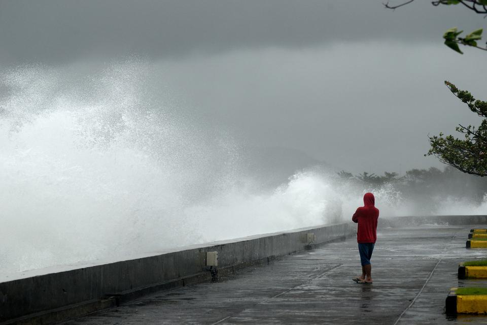Seorang pria mengamati gelombang tinggi di Manado, Sulawesi Utara, Indonesia, pada Selasa (14/2/2023).