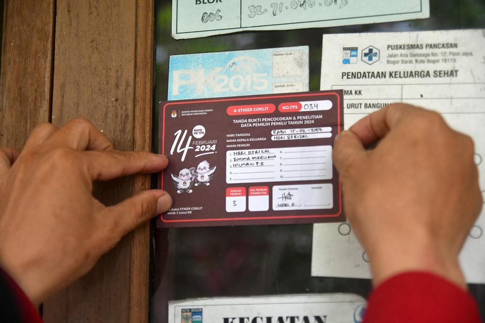 Petugas Pemutakhiran Data Pemilih (Pantarlih) menempelkan stiker usai pencocokan dan penelitian (Coklit) data pemilih Pemilu 2024 di rumah warga di Jabaru, Kelurahan Pasir Kuda, Kota Bogor, Jawa Barat, Senin (20/2/2023). 