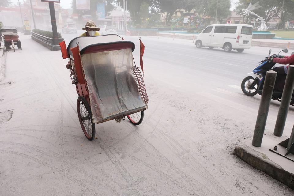 Sebuah becak melintas di jalan utama kota Magelang yang diselimuti abu vulkanis gunung Merapi di Magelang, Jawa Tengah, Sabtu (11/3/2023). Gunung Merapi kembali memuntahkan awan panas guguran (APG) pada pukul 12.12 WIB yang mengakibatkan hujan abu yang me