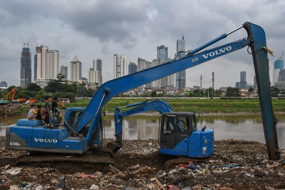 Anak-anak bermain di atas eskavator berlatar belakang gedung bertingkat di Jakarta, Selasa (14/3/2023). Bank Indonesia menyebutkan utang luar negeri Indonesia mencapai US$404,9 miliar pada Januari 2023.