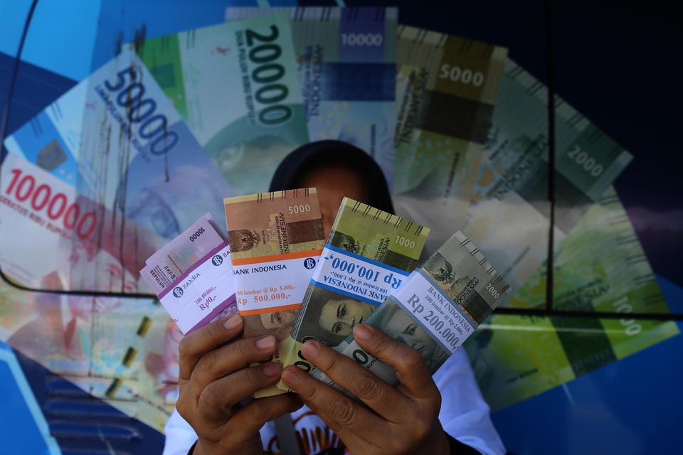 Warga menunjukan uang hasil penukaran di mobil kas keliling Bank Indonesia di Kota Ternate, Maluku Utara, Selasa (21/3/2023). 