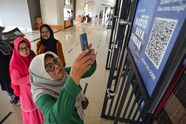 Pengunjung memindai QR code untuk mengisi buku tamu di Masjid Raya Sumatera Barat di Padang, Senin (27/3/2023). 