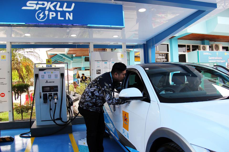 Seorang pegawai memberikan informasi kepada pengemudi sebelum melakukan test drive sebuah mobil listrik di Stasiun Pengisian Kendaraan Listrik Umum (SPKLU) PLN di Dumai, Riau, Jumat (31/3/2023). 