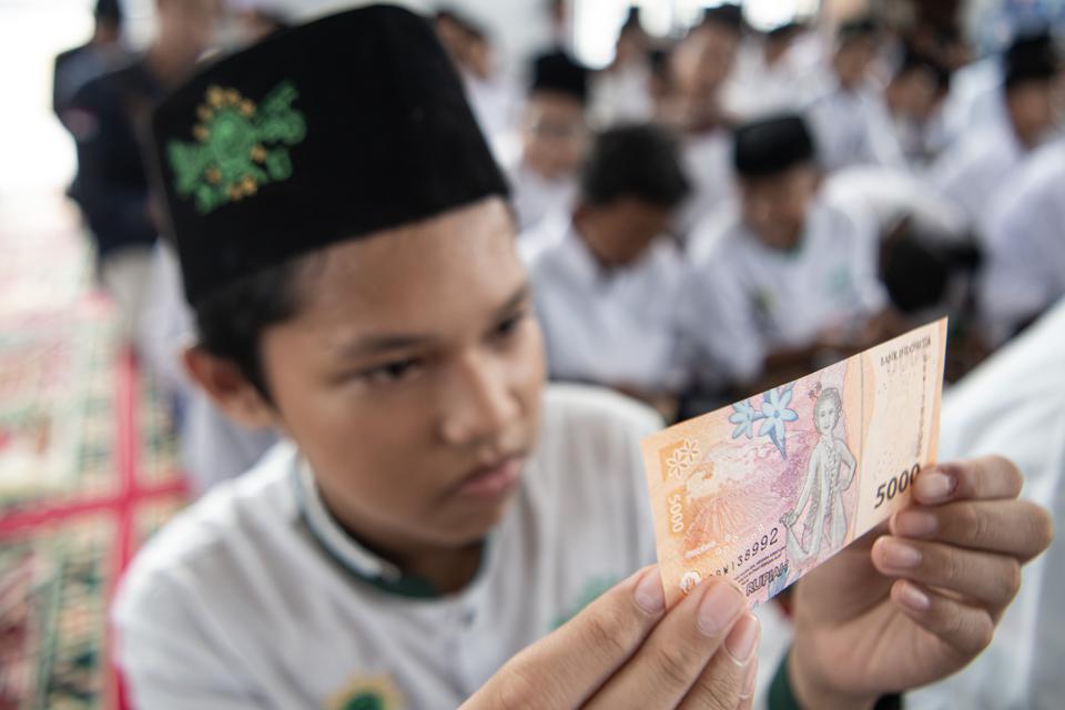 Santri mengamati uang pecahan Rp5 ribu saat peluncuran Program Gerakan Santri Cinta Rupiah Se-Sumatera Selatan di Pesantren Aulia Cendekia Palembang, Sumatera Selatan, Sabtu (1/4/2023). 