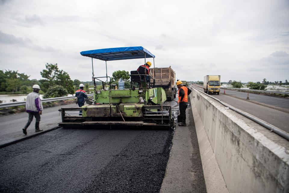 Pekerja dibantu alat berat menyelesaikan pengaspalan Jalan Tol Trans Sumatera ruas Kayu Agung-Palembang (Kapal) di Jejawi, Ogan Komering Ilir (OKI), Sumatera Selatan, Senin (3/4/2023).