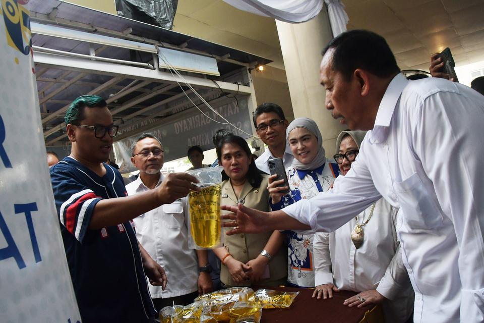 Menteri Perdagangan Zulkifli Hasan (kedua kiri) bersama selebritas Surya Utama alias Uya Kuya (kiri) saat memberikan MinyaKita kepada warga di Pasar Murah Ramadhan, Kalibata, Jakarta Selatan, Selasa (4/4/2023). Menurut Mendag pasar murah Ramadhan itu dala