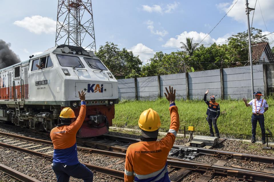 Pekerja menyapa masinis usai perbaikan wesel rel kereta api di perlintasan Kabupaten Ciamis, Jawa Barat, Sabtu (8/4/2023). 