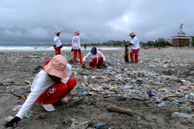 Petugas membersihkan pesisir pantai dari sampah plastik yang berserakan di Pantai Kuta, Badung, Bali, Kamis (13/4/2023). Sampah plastik kiriman yang terdampar terbawa arus laut dan mengotori kawasan Pantai Kuta itu kembali terjadi diperkirakan karena kond