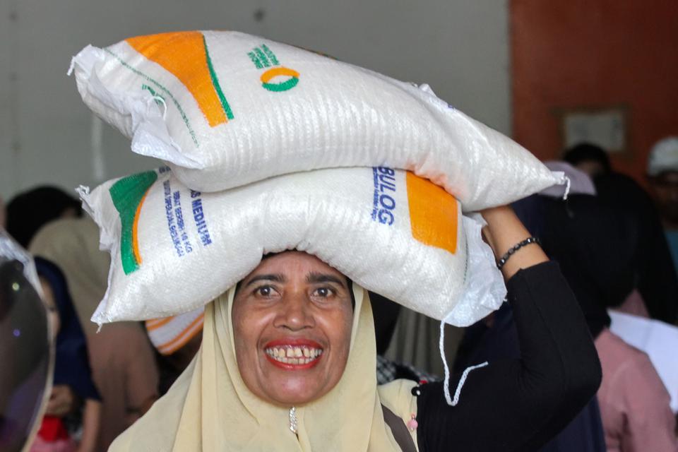 Warga dari Keluarga Penerima Manfaat (KPM) membawa beras saat penyaluran Bantuan Cadangan Beras Pemerintah (BCBP) di Kantor Pos Lhokseumawe, Aceh, Kamis (13/4/2023).