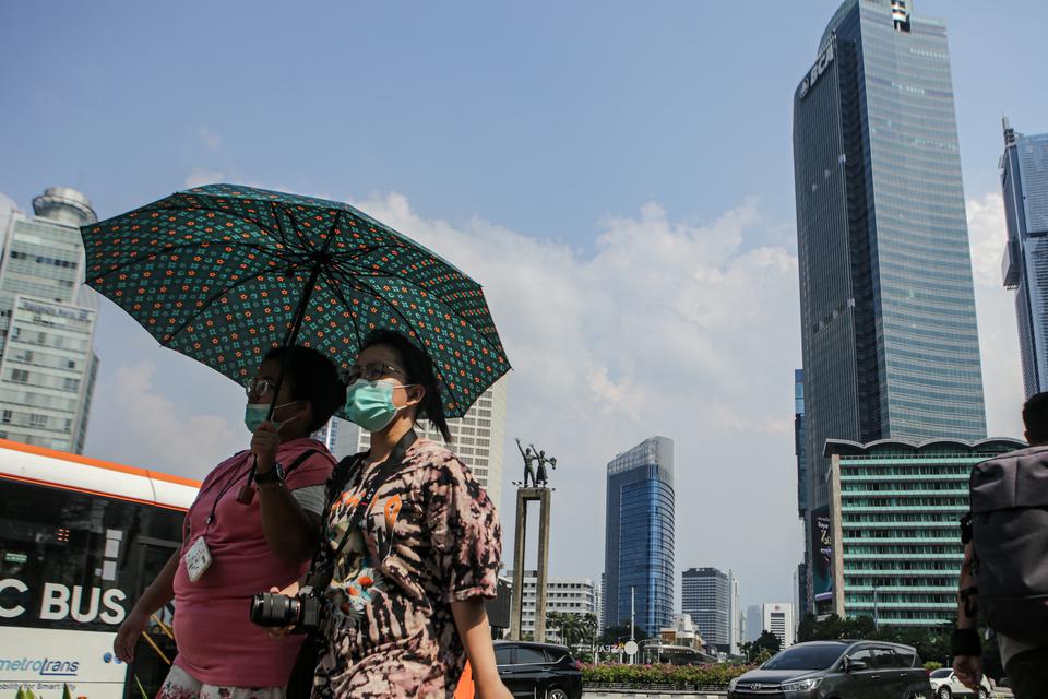Warga berjalan di tengah cuaca terik di kawasan Bundaran HI, Jakarta, Senin (24/4/2023).
