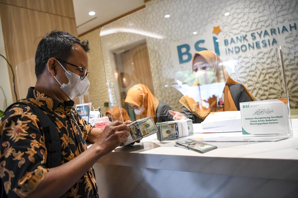 Nasabah membawa uang dolar AS usai bertransaksi di Kantor Cabang BSI Jakarta Thamrin, Jakarta, Kamis (11/5/2023). PT Bank Syariah Indonesia Tbk (BSI) menyatakan bahwa layanan ATM antarbank telah kembali berangsur pulih dan dapat dilakukan nasabah melalui 
